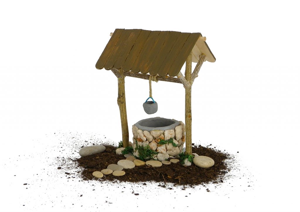 figura en miniatura de un pozo para decorar el nacimiento hecha con plastilina, ramas secas, palos planos y piedras pequeñas