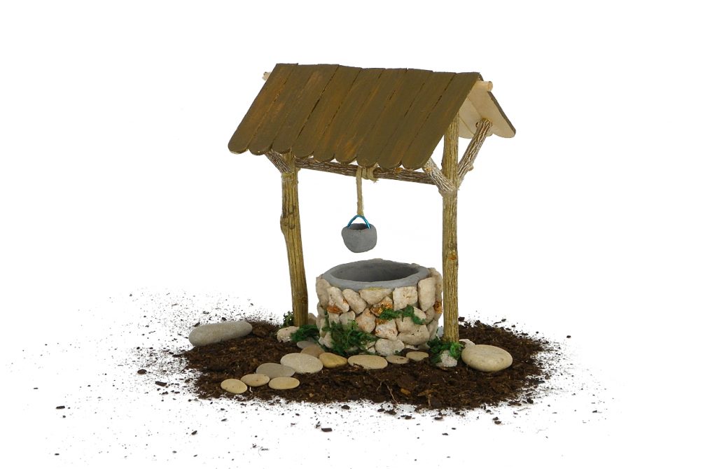 figura en miniatura de un pozo para la decoracion del nacimiento hecha con plastilina, ramas secas, palos planos y piedras pequeñas