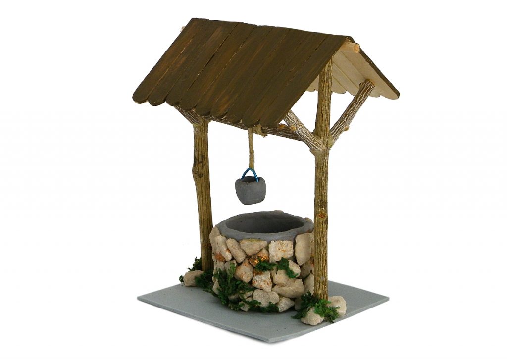 pozo en miniatura para la decoracion del belen hecho con plastilina ramas secas piedras y palos planos