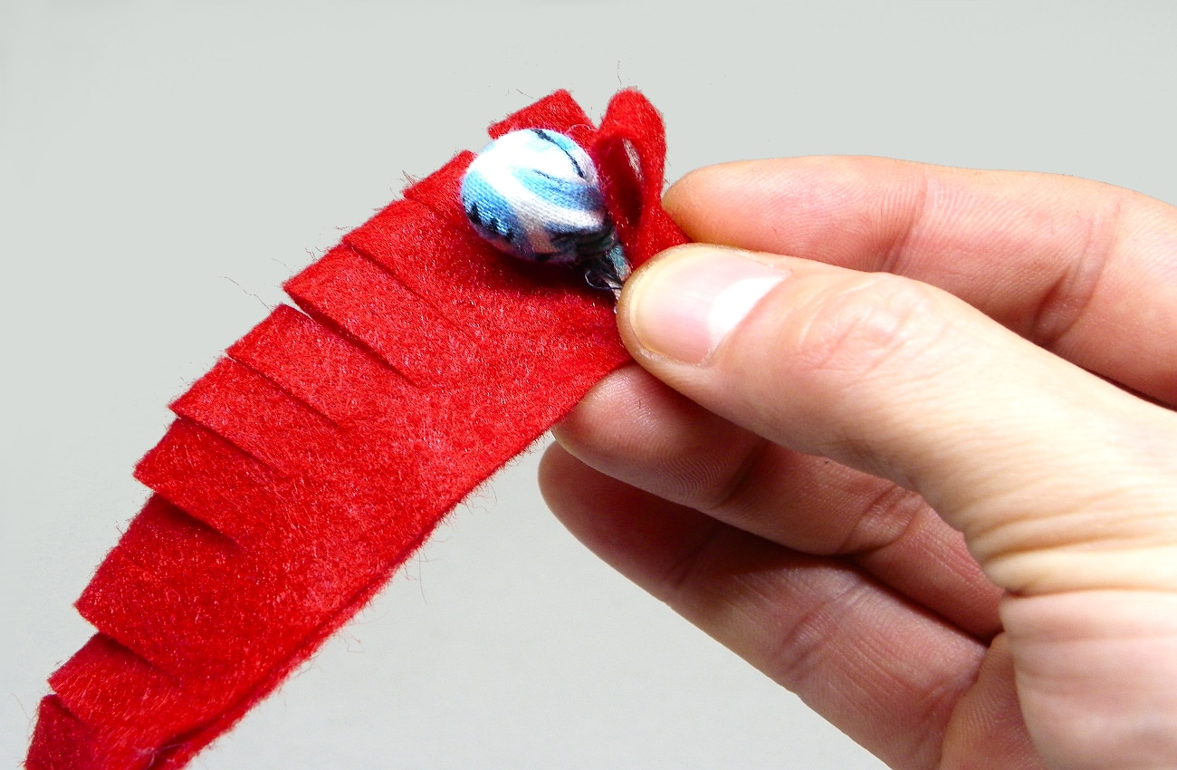 colocando pequeña bola de tela en el interior de la tira con flecos de fieltro para hacer flor roja1