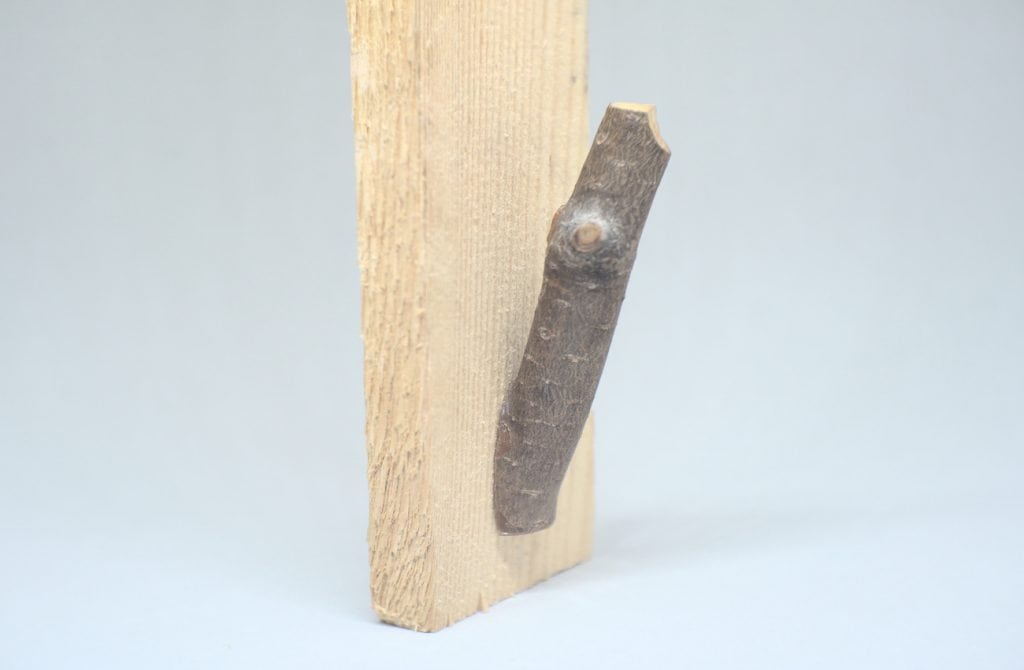 liston de madera con rama seca sujeta por un taco de madera