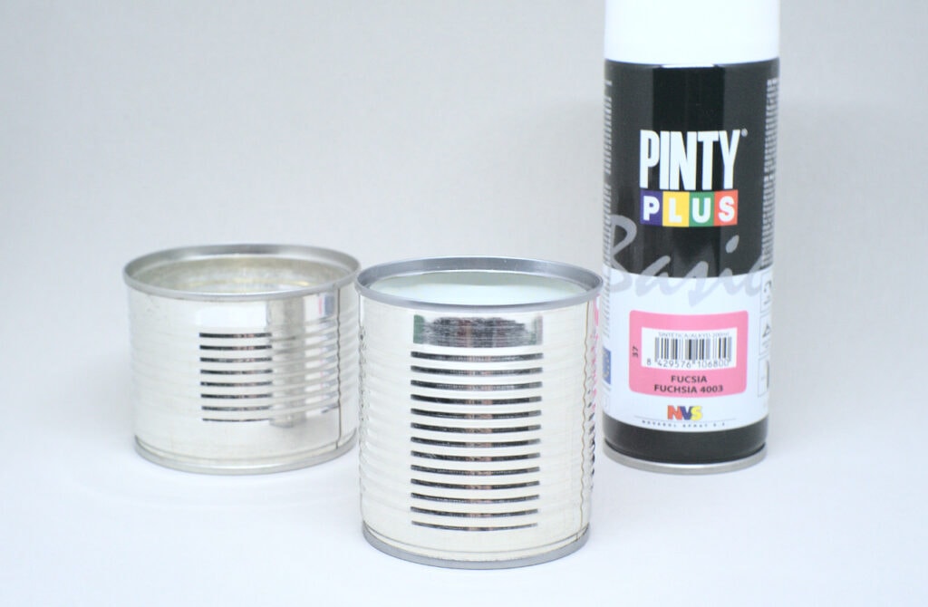 dos latas metalicas de conservas y bote de pintura en spray color fucsia