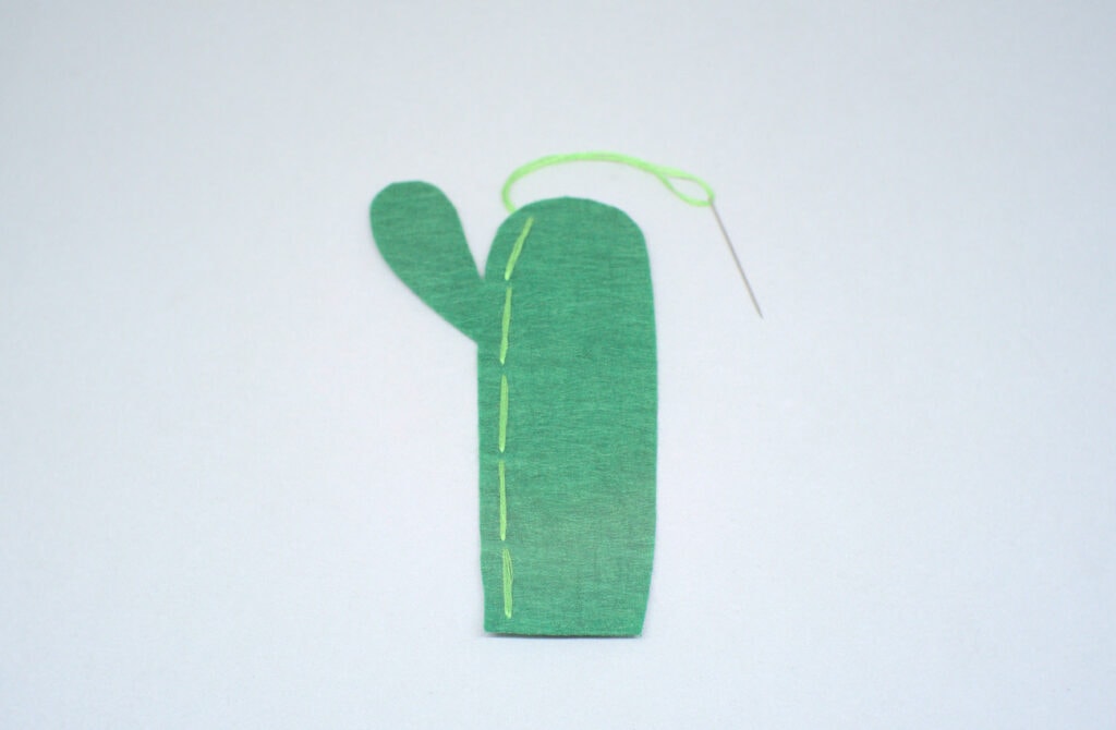 puntadas dobles de hilo verde en pieza de fieltro con forma de cactus