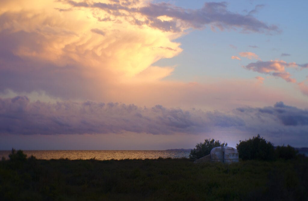 cumulo de nubes y estructura militar visto desde la playa de la gola en santa pola