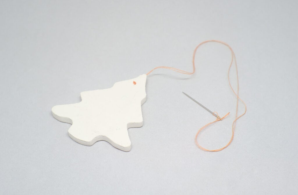 figura de pasta de un arbol navideño con hilo de coser para colgar