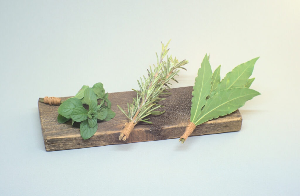 ramilletes de hierbas aromaticas albahaca romero y laurel sobre liston de madera