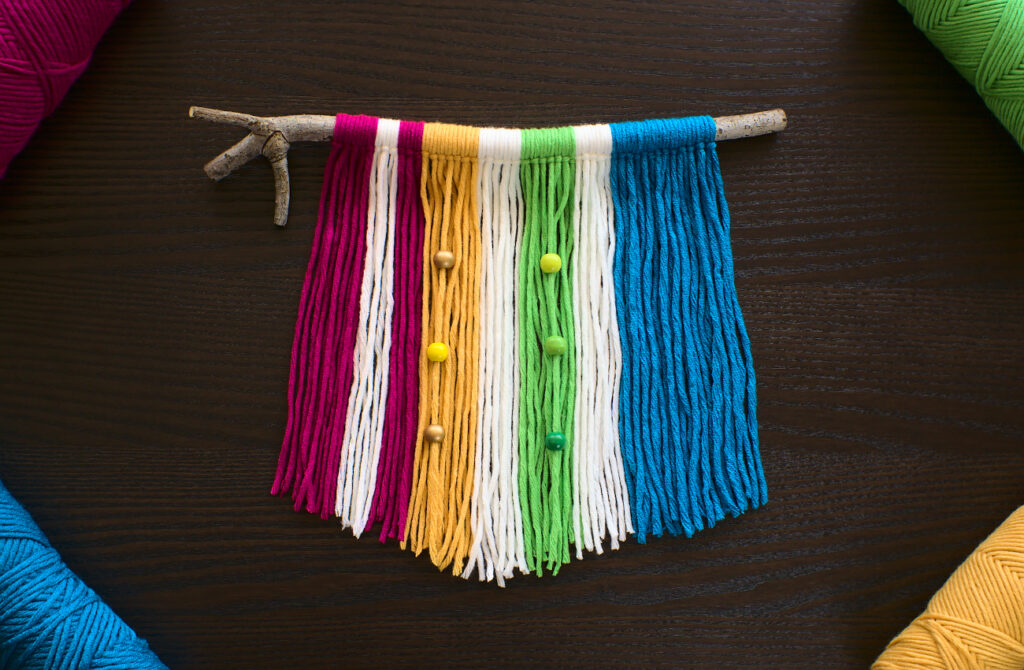 tapiz de pared hecho con lana de colores y una rama seca