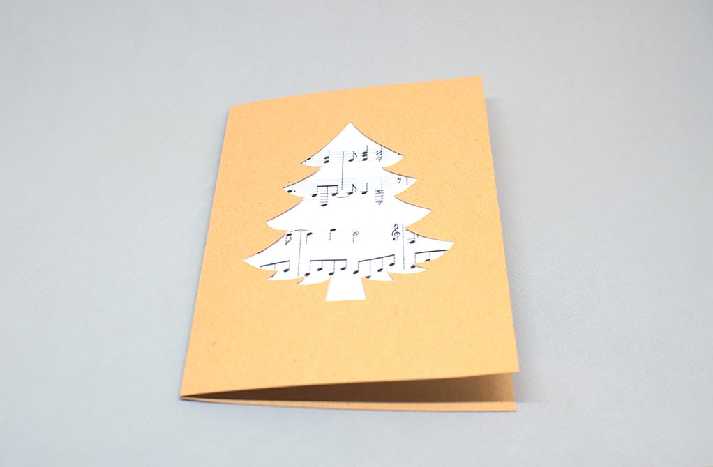 tarjeta de navidad con silueta de abeto con partitura