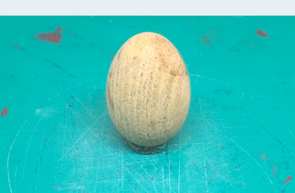 huevo de madera para zurcir adherido sobre alfombrilla de corte