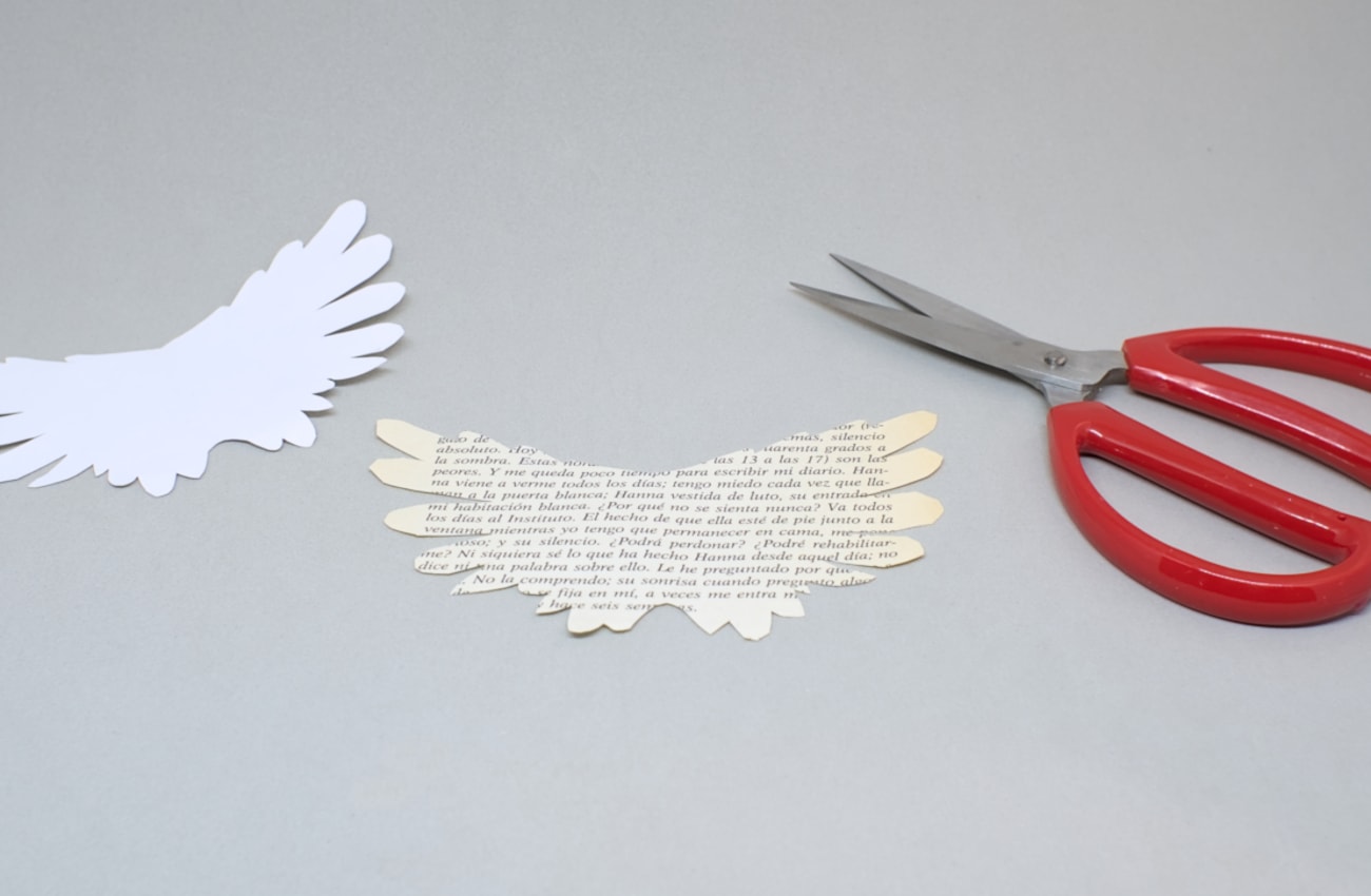 alas de angel hechas con hoja de papel de libro recortadas con plantilla
