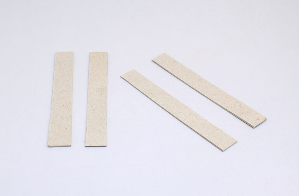 cuatro piezas rectagunlares de carton de 11 x 2 cm
