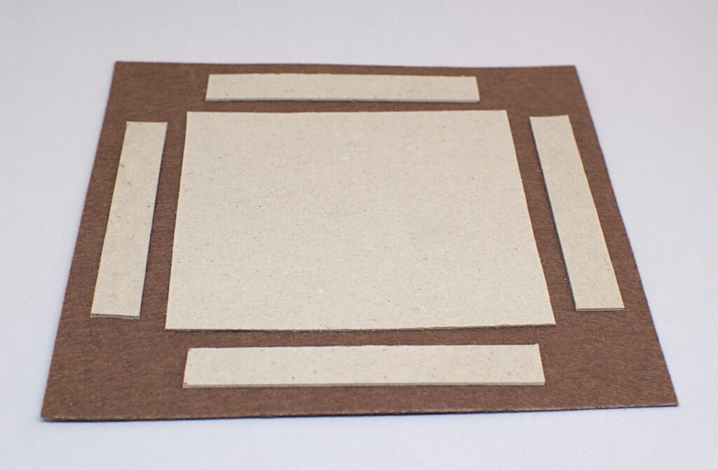 piezas de carton rectangulares adheridas sobre pieza de fieltro marron