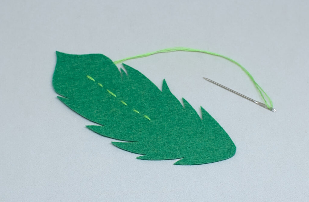 puntadas de hilo verde para representar calamo de pluma