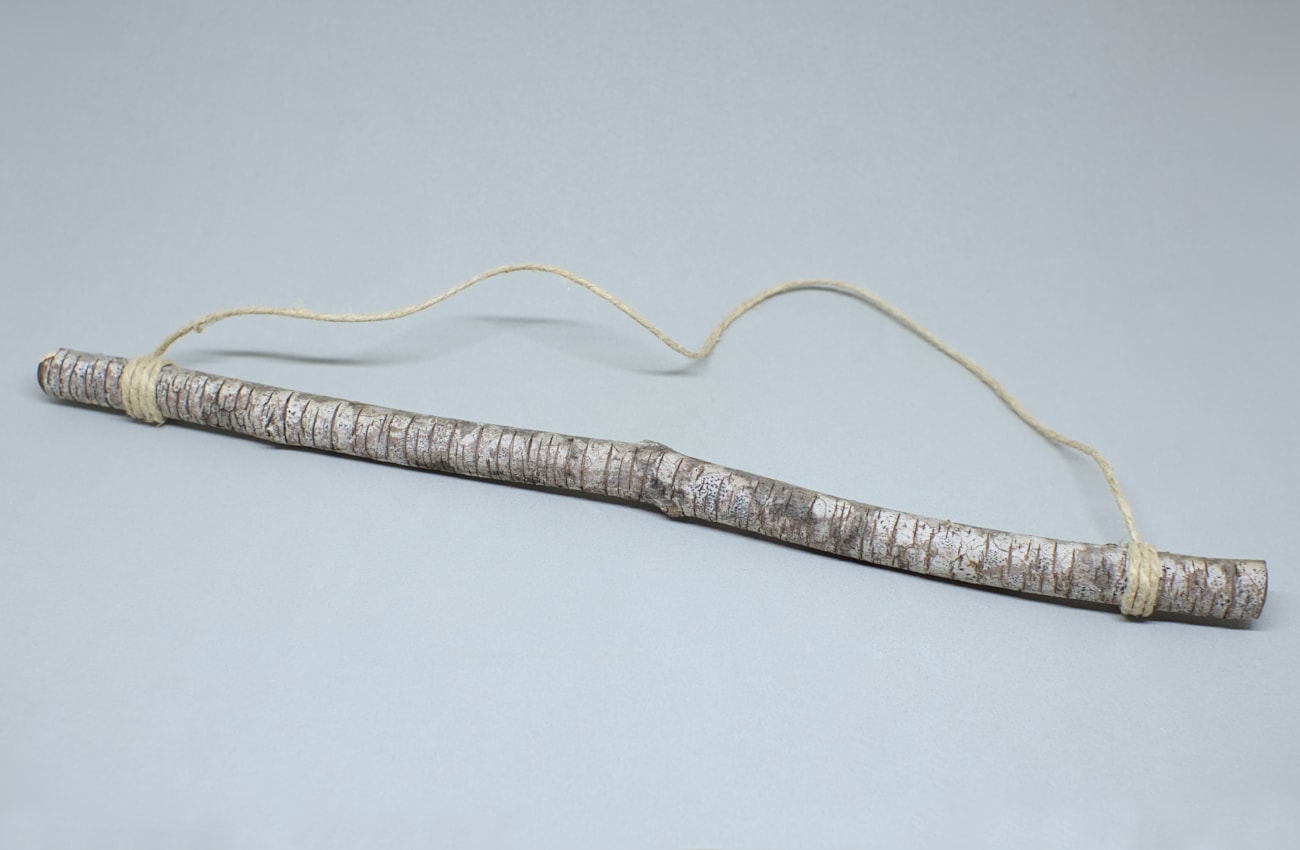 rama seca de pino con cuerda de yute anudada en ambos extremos