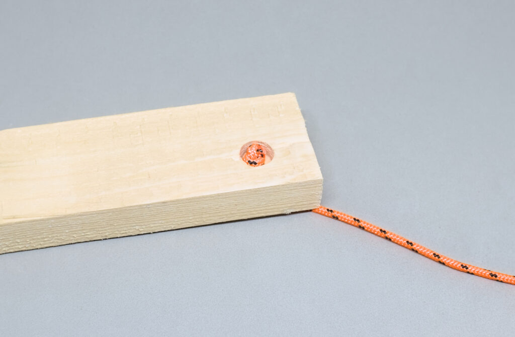 cuerda cordino con nudo simple dentro del orificio de la madera