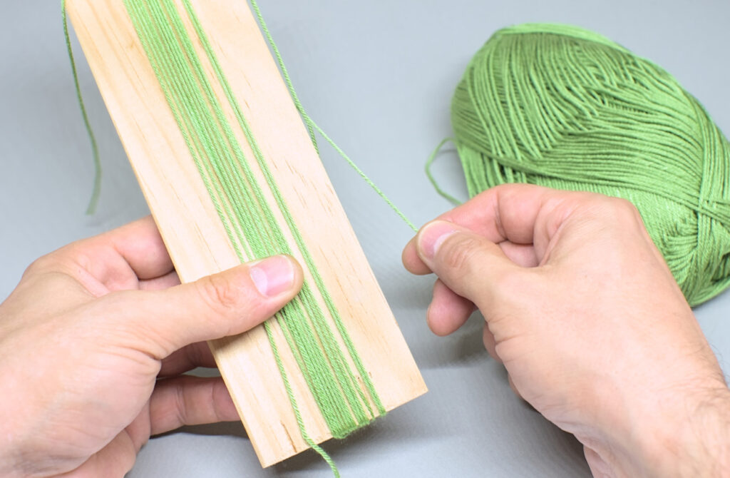 enrollando liston de madera con hilo perle para hacer borla