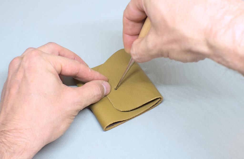 marcando cuero con punzon para segundo orificio de broche a presion