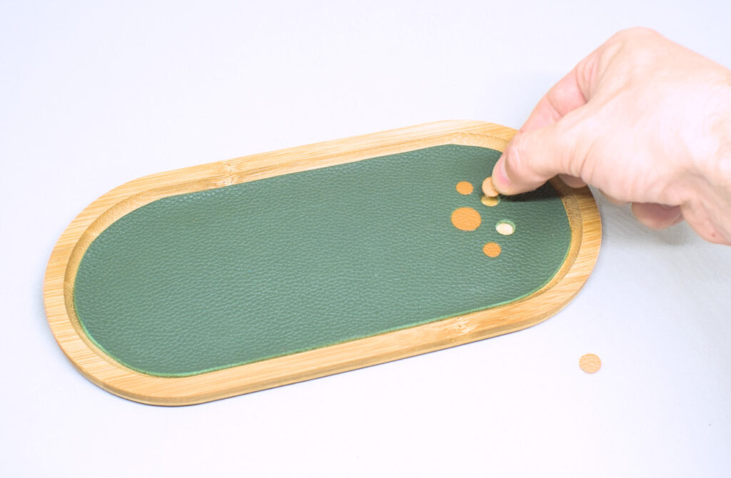 colocando circulos de cuero en patron decorativo para bandeja de madera