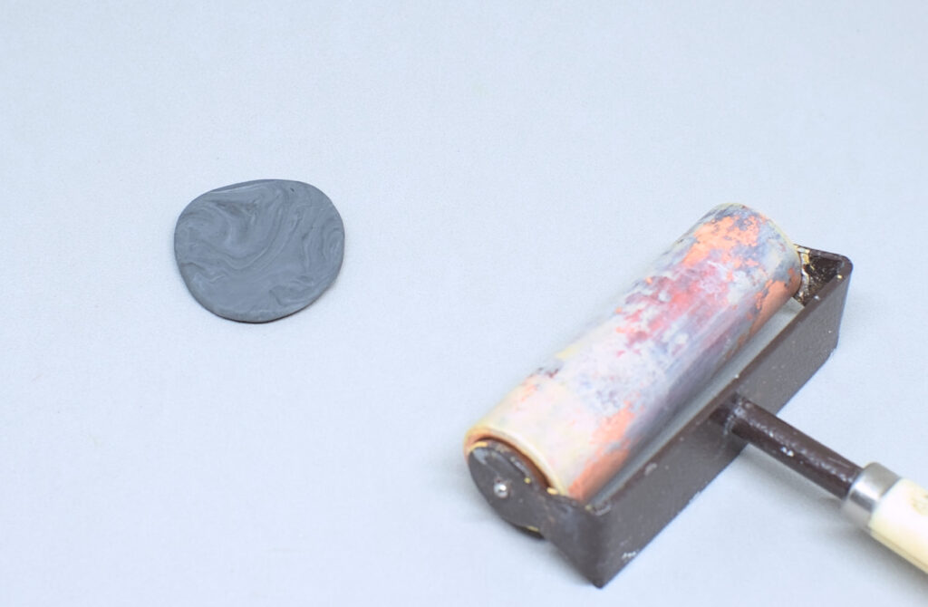 bola de plastilina en gris aplastada con rodillo de modelar