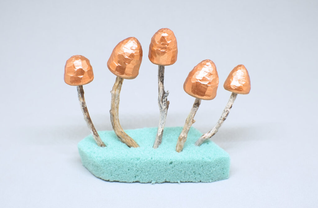 pequeñas setas tallas en madera y pintadas en cobre metalizado
