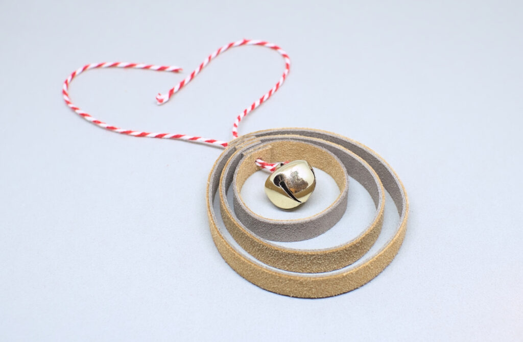 colgante de navidad con forma de bola hecho con aros de cuero y cascabel
