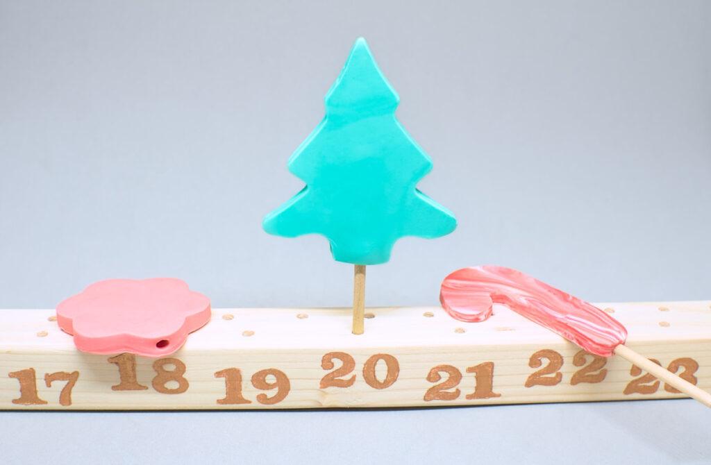 figuras de navidad de plastilina y liston de madera con numeros para calendario de adviento