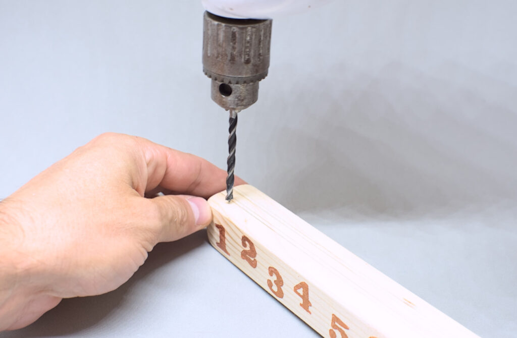 haciendo orificios en liston de madera para calendario de adviento