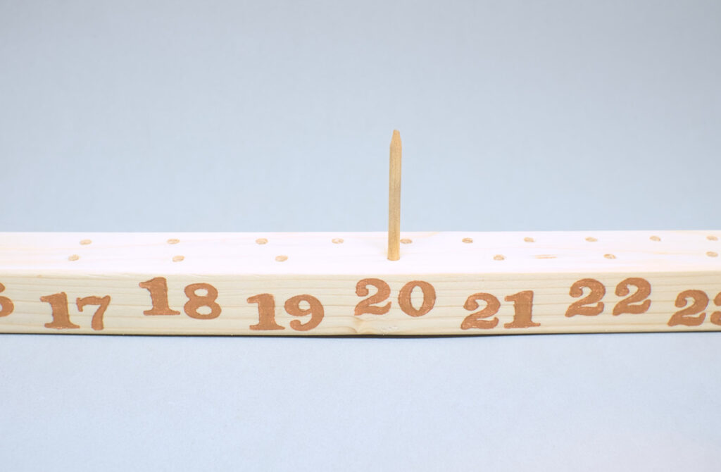 liston de madera con orificios y calendario estampado