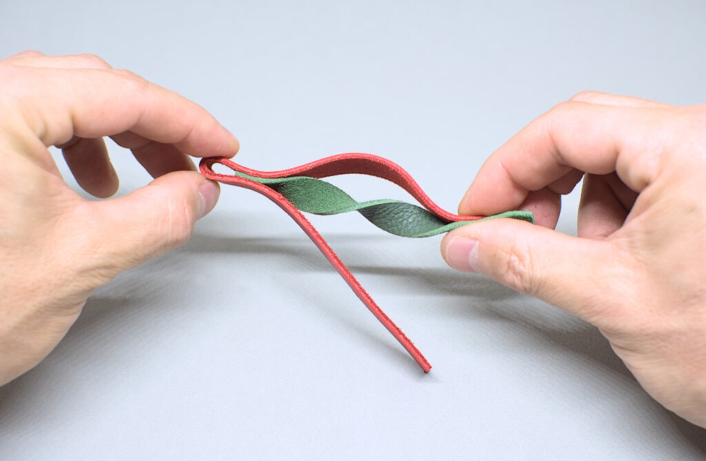retorciendo tira de cuero verde para hacer colgante navideño de peonza