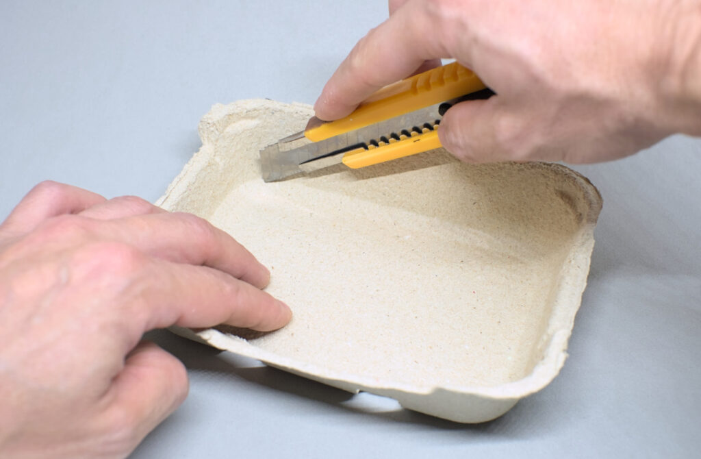 cortando tapa de cartón de una huevera