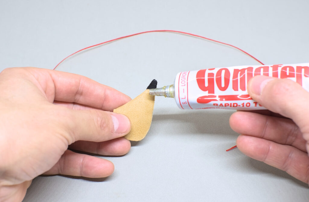 echando pegamento de contacto para adherir hilo encerado en mini bota de vino