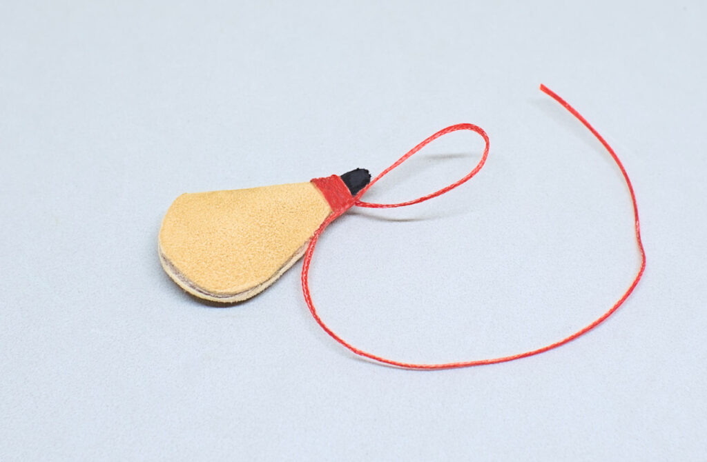 haciendo bucle de hilo encerado en cuello de bota de vino en miniatura