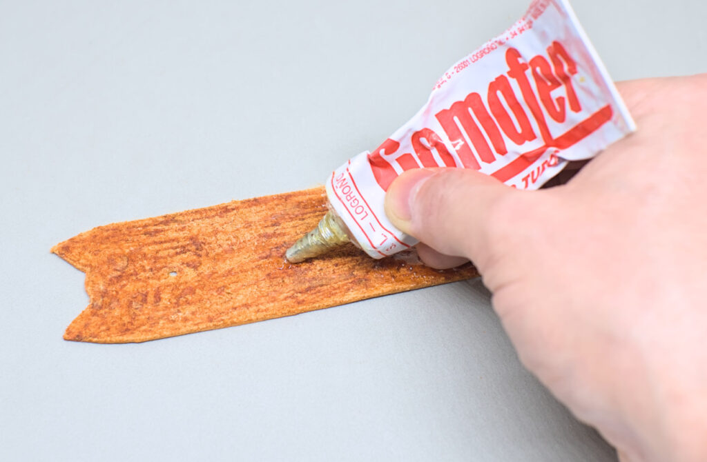 echando pegameto de contacto en reverso de pieza de cuero