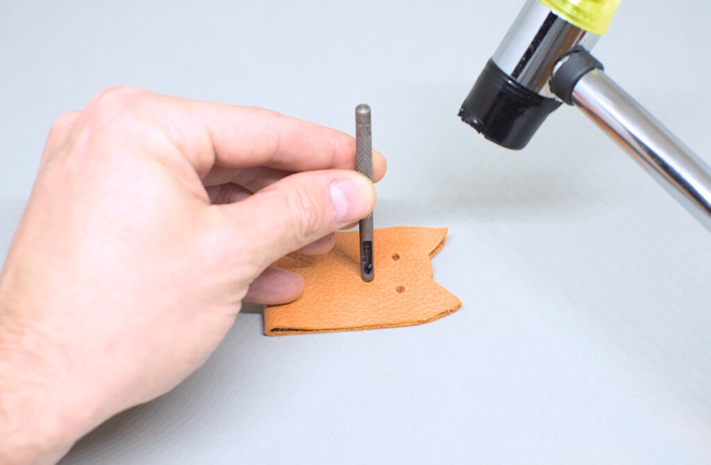 haciendo orificios en tira de cuero para colocar broche a presion