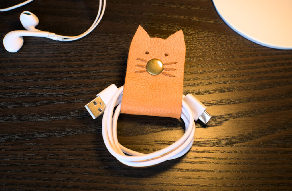 organizador de cables hecho con cuero y forma de gatito