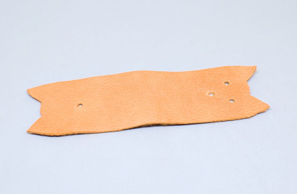 orificios hechos en tira de cuero para colocar boton a presion