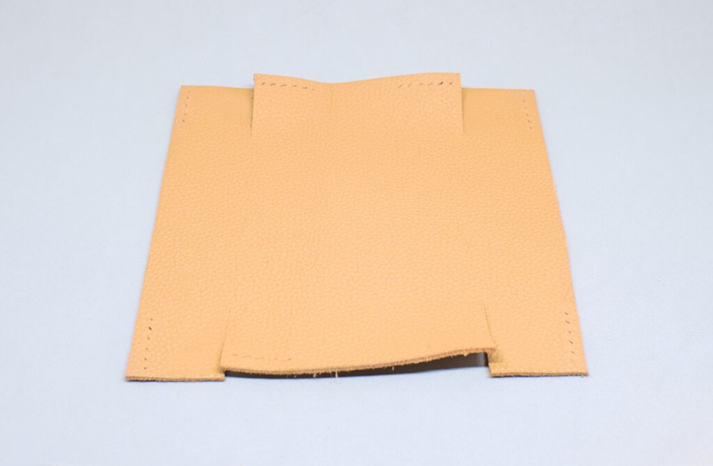 pieza de cuero cuadrada con cortes paralelos y orificios de linea de costura