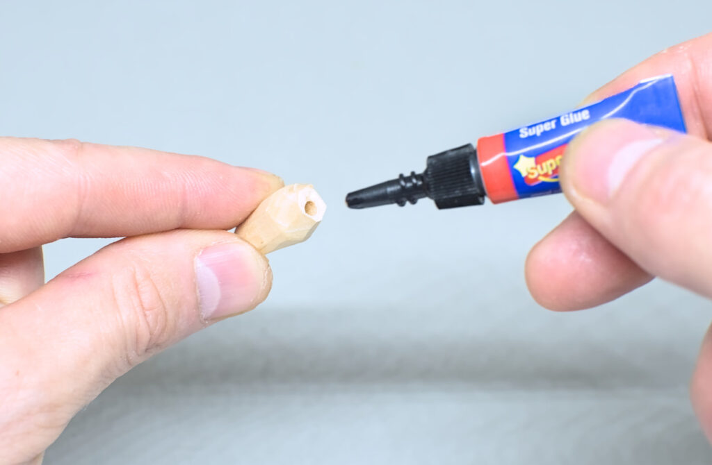 echando pegamento super glue en orificio de pieza de madera para pendientes