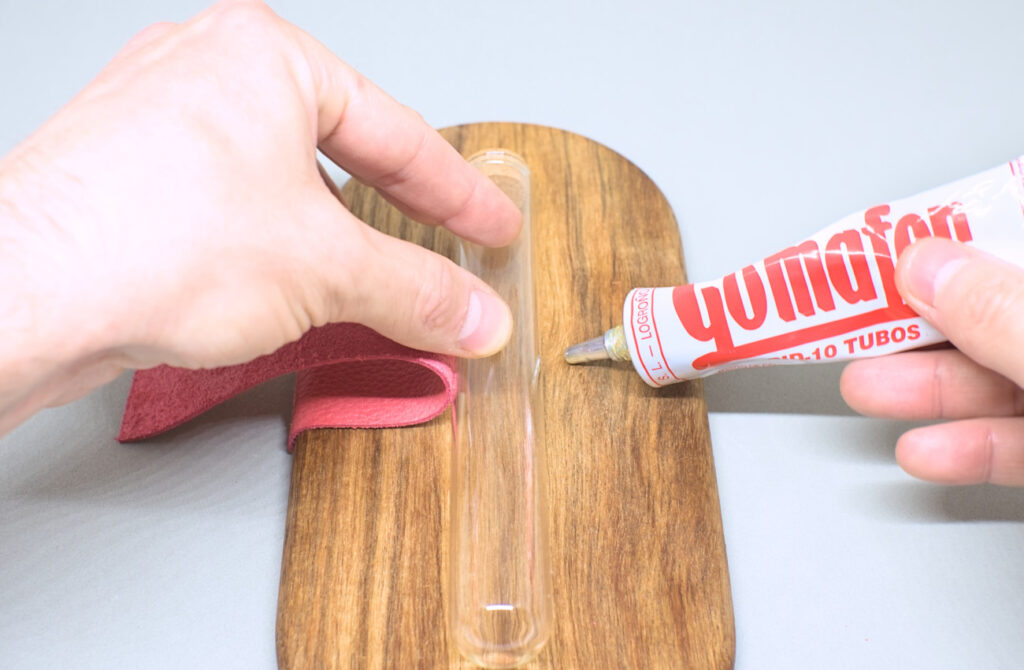adhiriendo tira de cuero en bandeja de madera para sujetar tubo de cristal