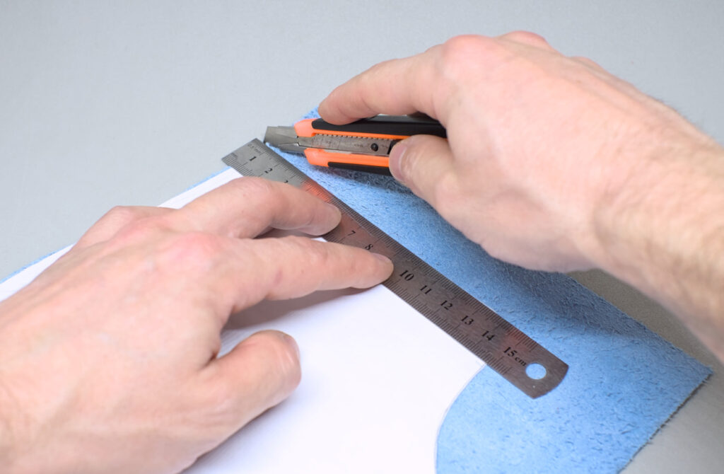 cortando pieza de cuero para estuche de gafas con patron y cuter