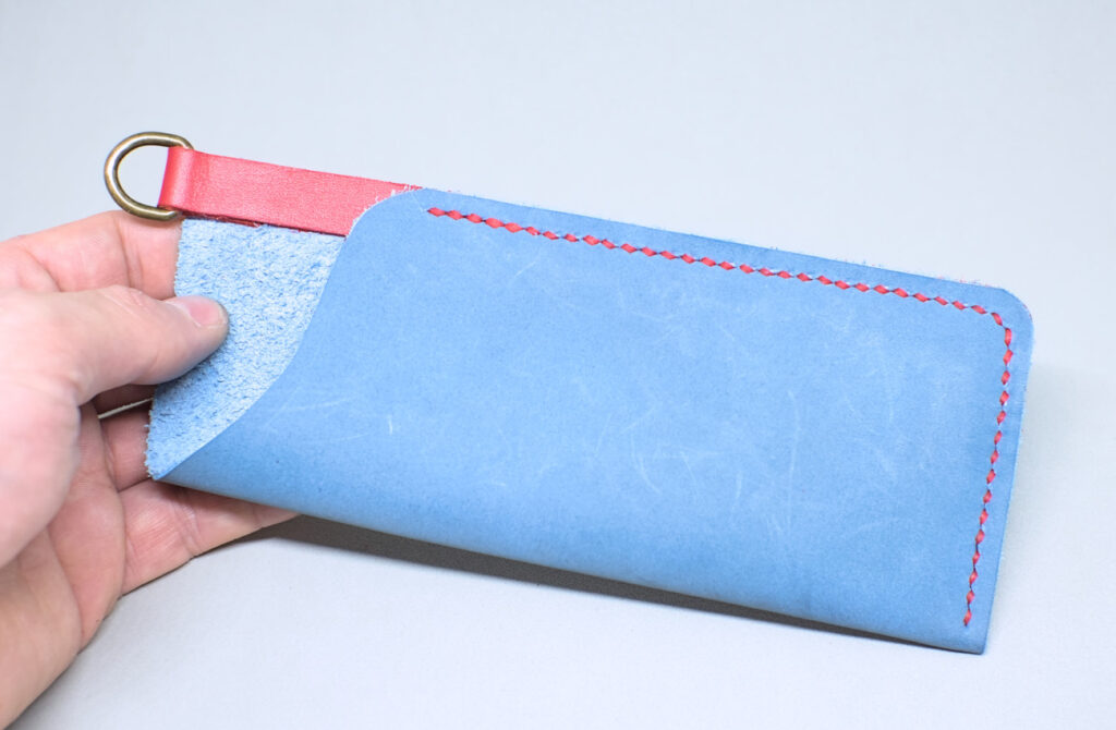 costura hecha con hilo encerado en contorno de estuche de cuero para gafas