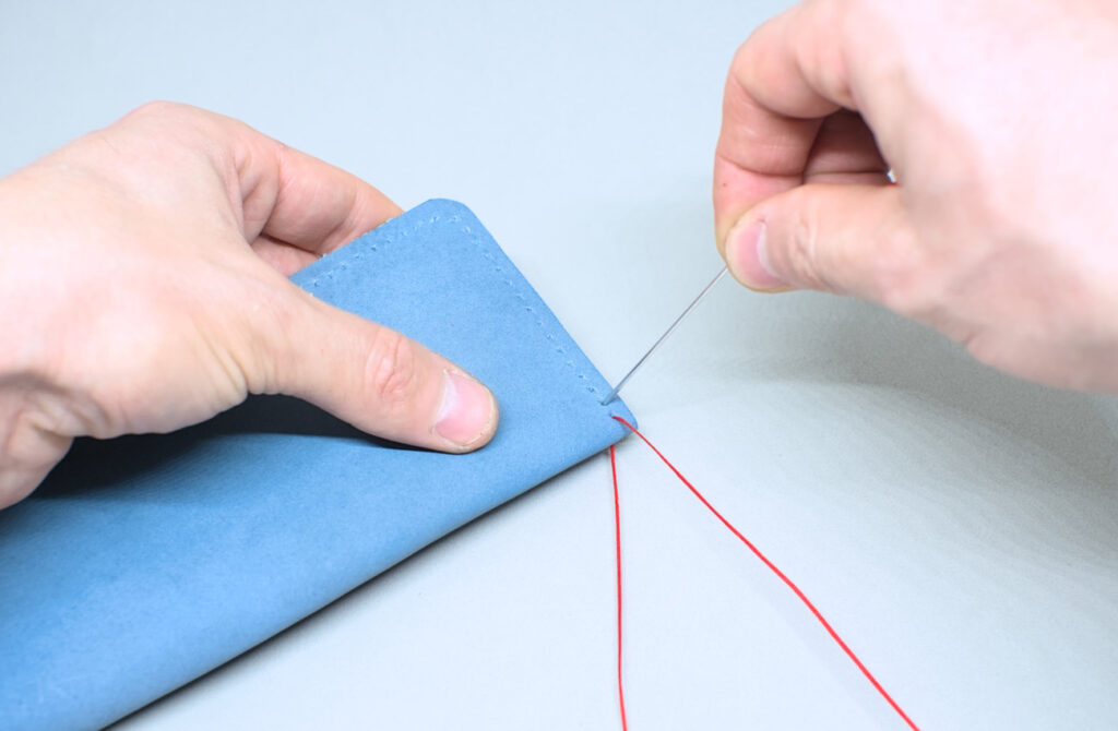 dando la primera punta con aguja e hilo encerado en linea de costura de estuche de cuero