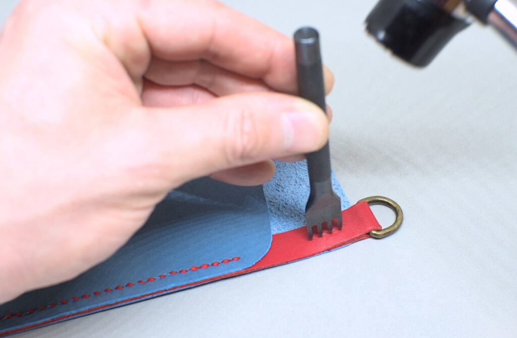 perforando tira de cuero rojo en union con tenedor de cuatro puntas
