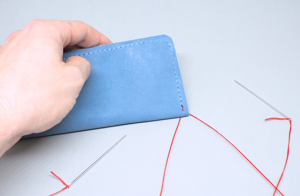 primera puntada de hilo encerado en anverso de estuche de cuero