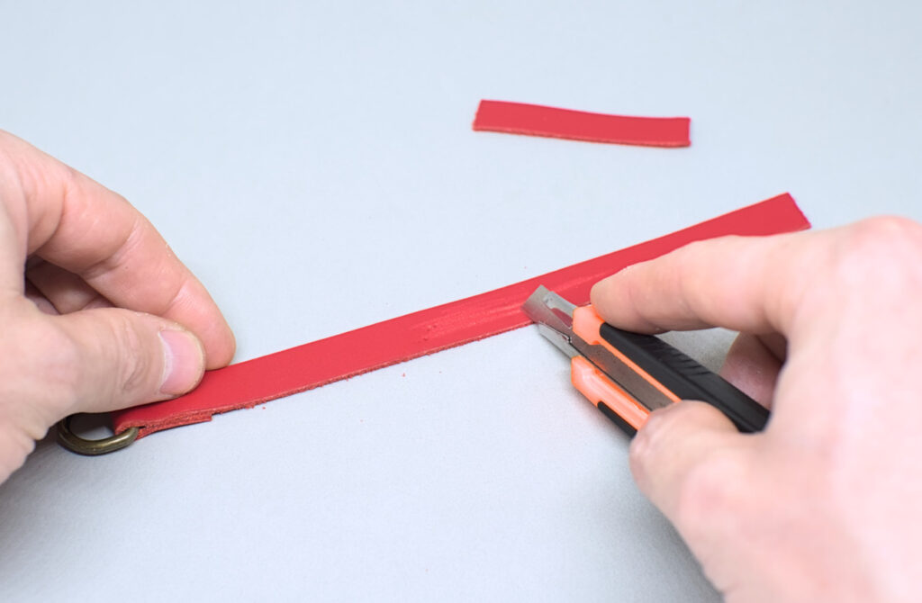 raspando con cuter parte pulida de tiras de cuero rojo