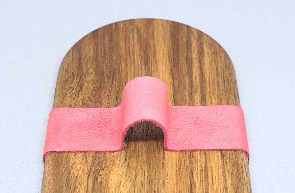 tira de cuero adherida sobre bandeja de madera con la forma del tubo