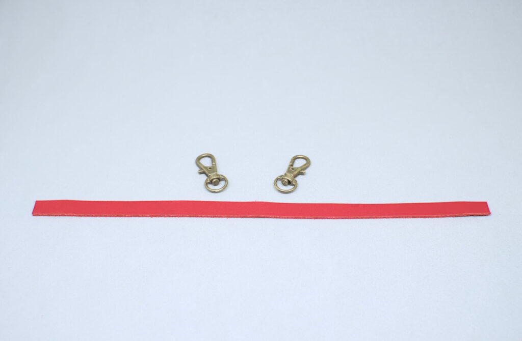 tira de cuero rojo y mosquetones giratorios de metal