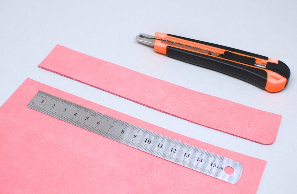 tira de cuero rosa cortada con cuter y regla