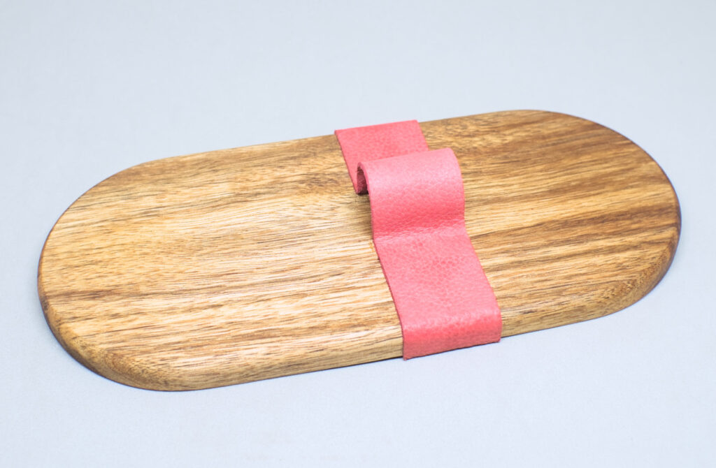 vista lateral tira de cuero adherida sobre bandeja de madera con la forma del tubo