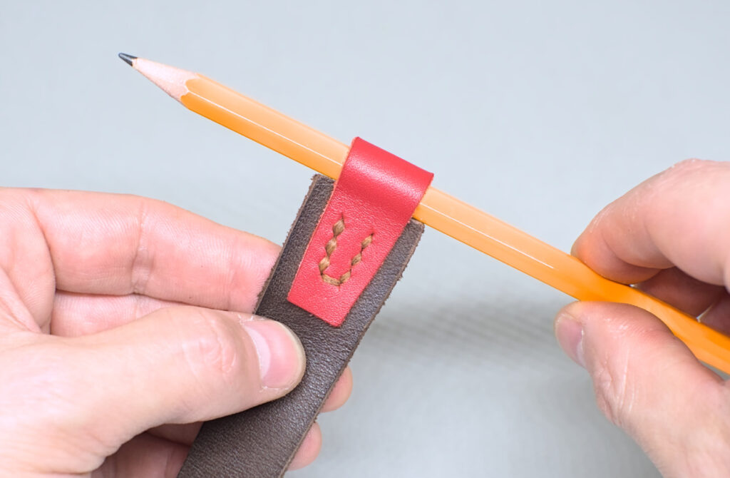 colocando lapiz en portalapiceros hecho en marcapaginas de cuero